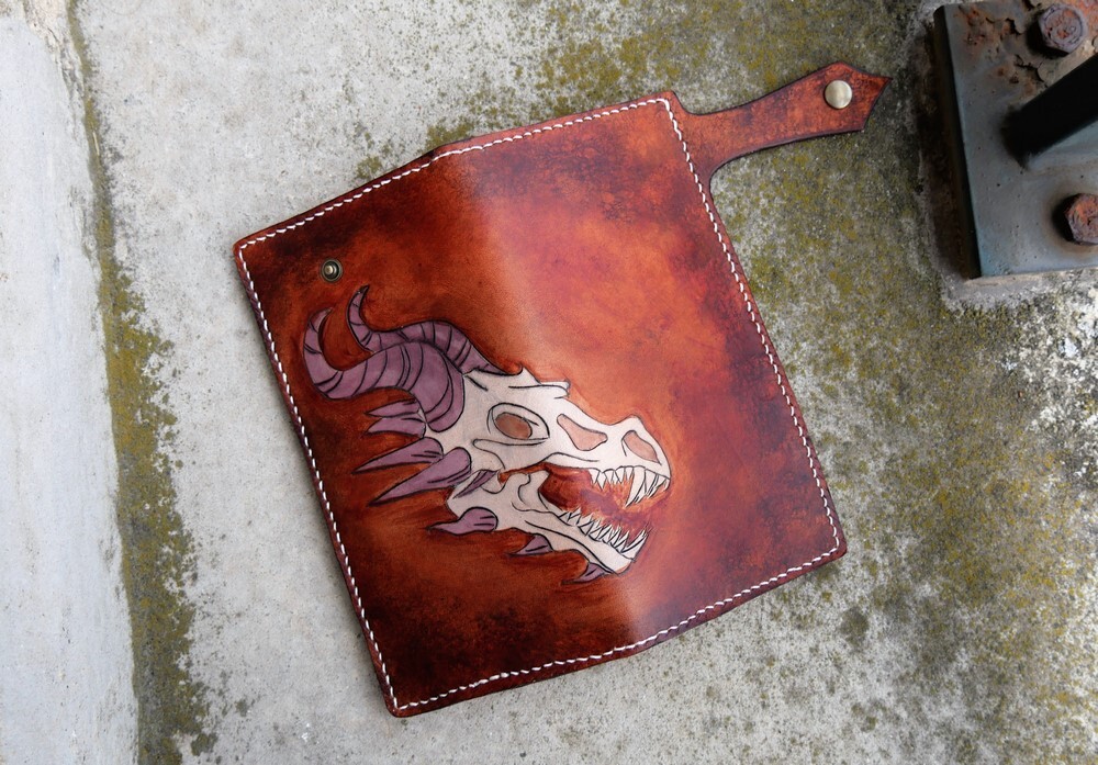 Détail d'un portemonnaie représentant un crâne de dragon sur un fond marron en dégradé